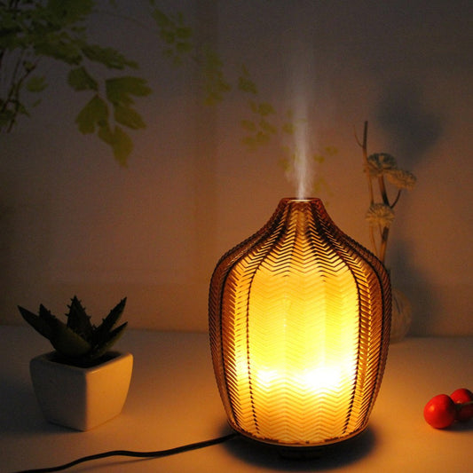AmberGlow diffuser glowing with warm yellow light in a dim, cozy room setting